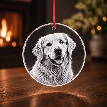 Ornement rond en cristal 2D gravé avec le portrait d’un Golden Retriever, suspendu à un ruban rouge dans une chaleureuse ambiance de fêtes.