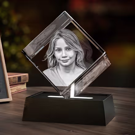 Cristal photo 3D en forme de diamant gravé avec le portrait d’une jeune fille souriante, présenté sur une base lumineuse LED noire à côté de la photo originale.